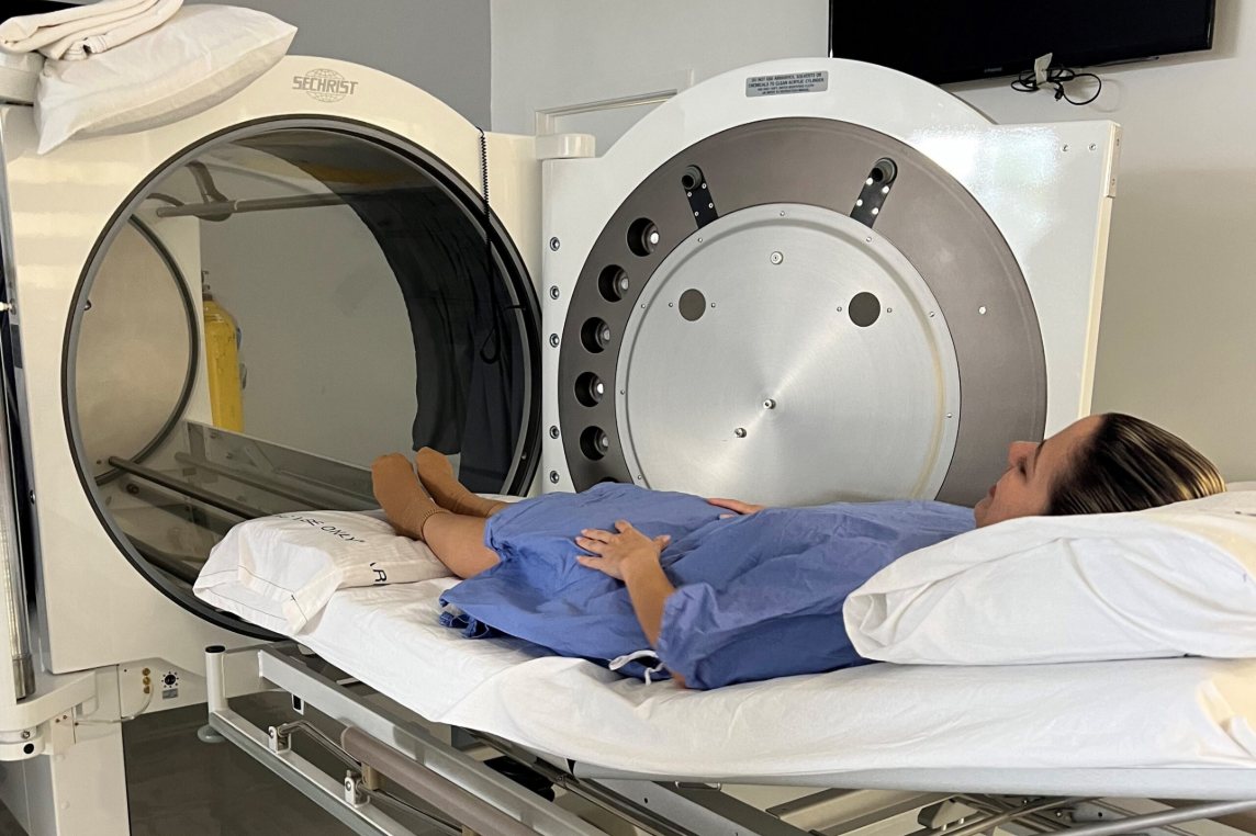A patient resting on the bed of a monoplace hyperbaric chamber at Kendall South Medical Center